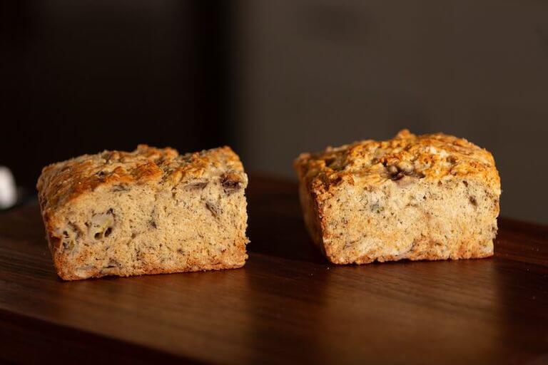 A cross-section of a fresh banana bread loaf on a wooden surface.