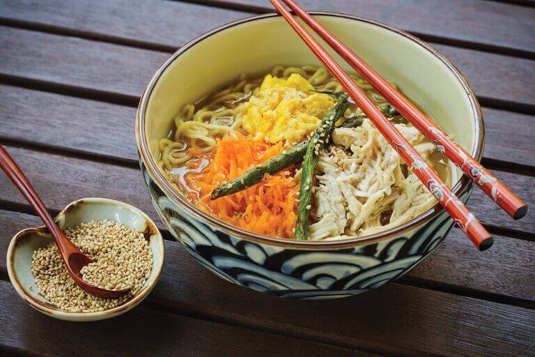 A dish of Ginger Chicken Ramen with chopsticks placed across the top.