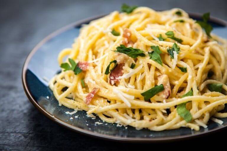 A heaping plate of pasta with a sprinkling of shaved cheese and herbs.