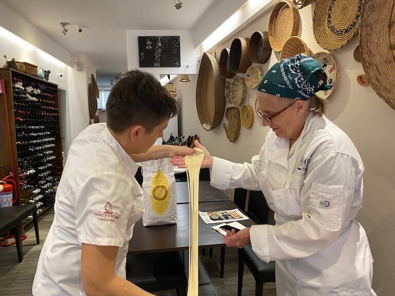 Chef Dawn and another pastry chef making Su Filindu pasta in a kitchen in Italy.