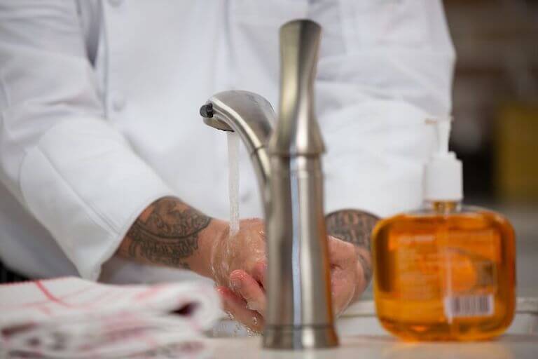 Chef washing hands at a sink.
