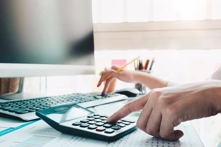 Hand using calculator while holding pencil for culinary school financial planning