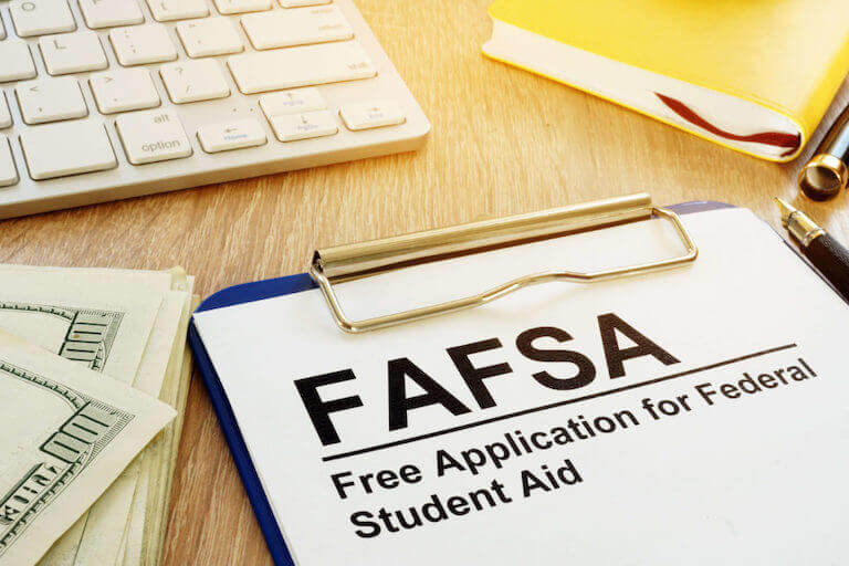 FAFSA document on a clipboard next to a stack of hundred dollar bills