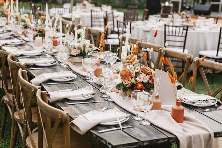Long wooden banquet table decorated with candles and flowers outside