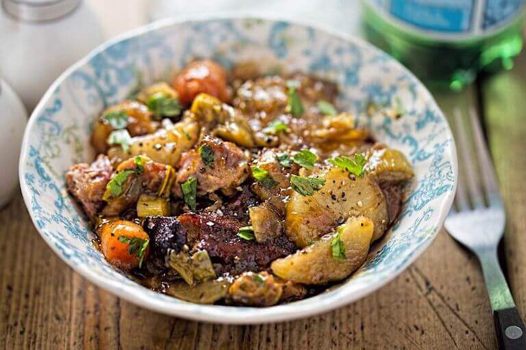 Slow roasted lamb with carrots served in a blue and white bowl.