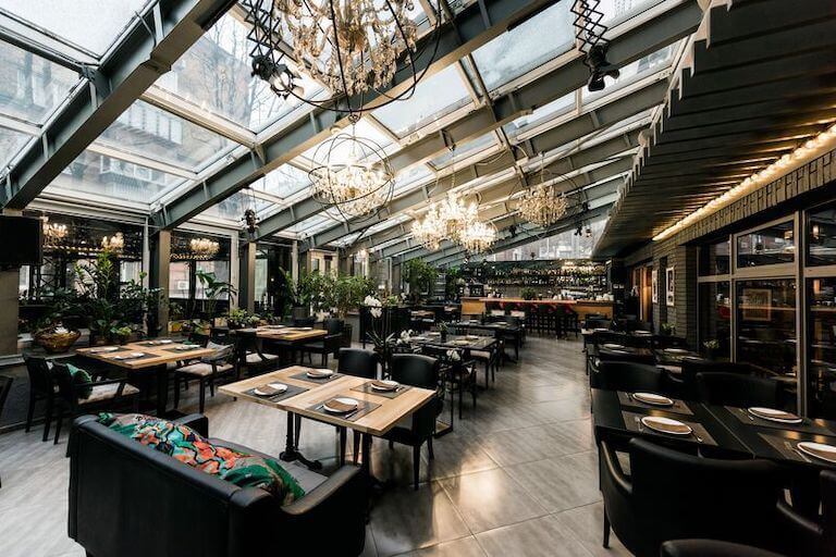 Interior of a modern-style restaurant with dark wood tables and chunky black chairs.