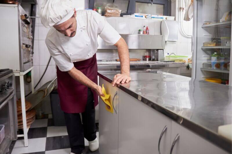 Chef wiping down a kitchen counter.